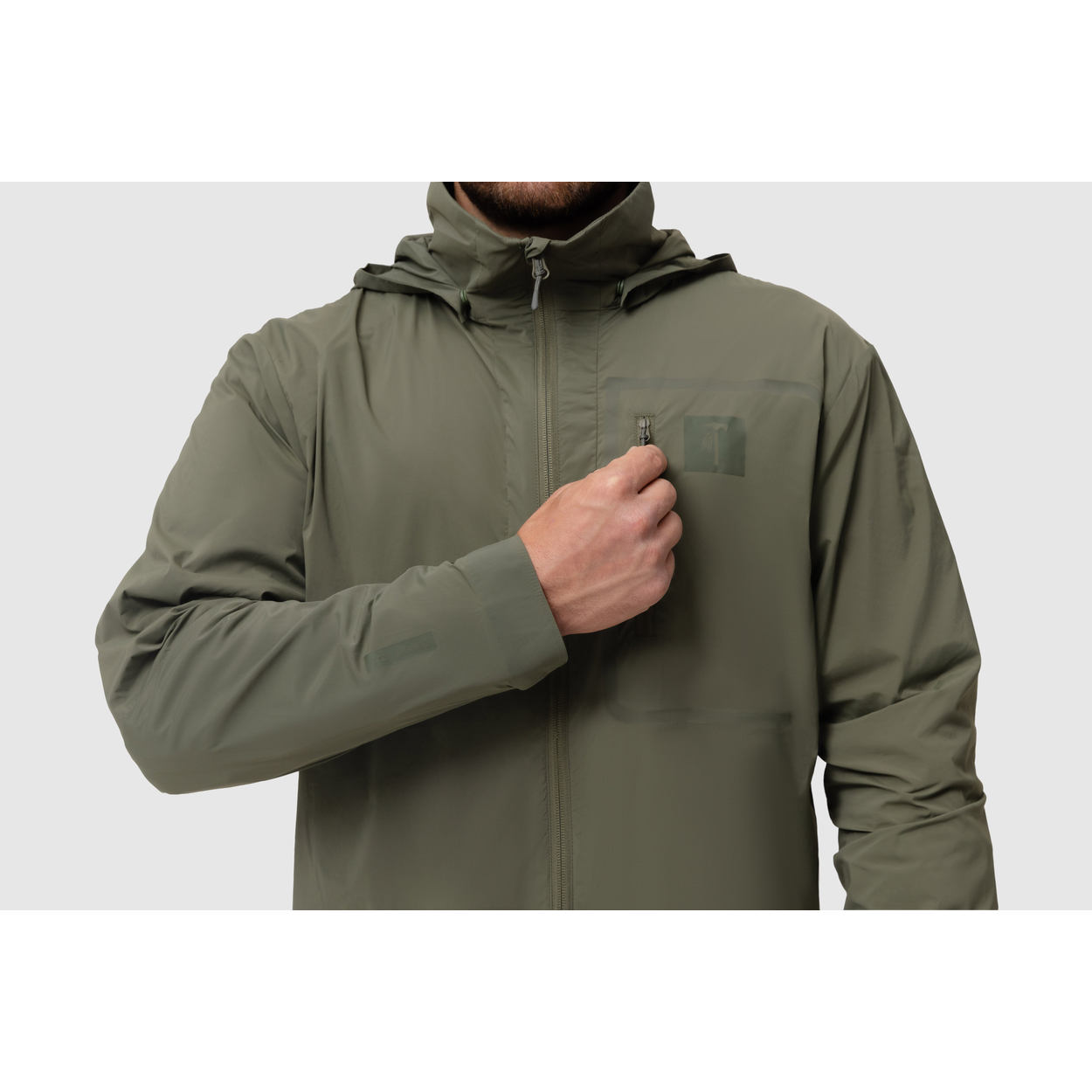 Front close-up photo of the Tomahawk Performance Crosswind Jacket, a tactical windbreaker, depicting the chest pocket and attachment point in Ranger Green color way.