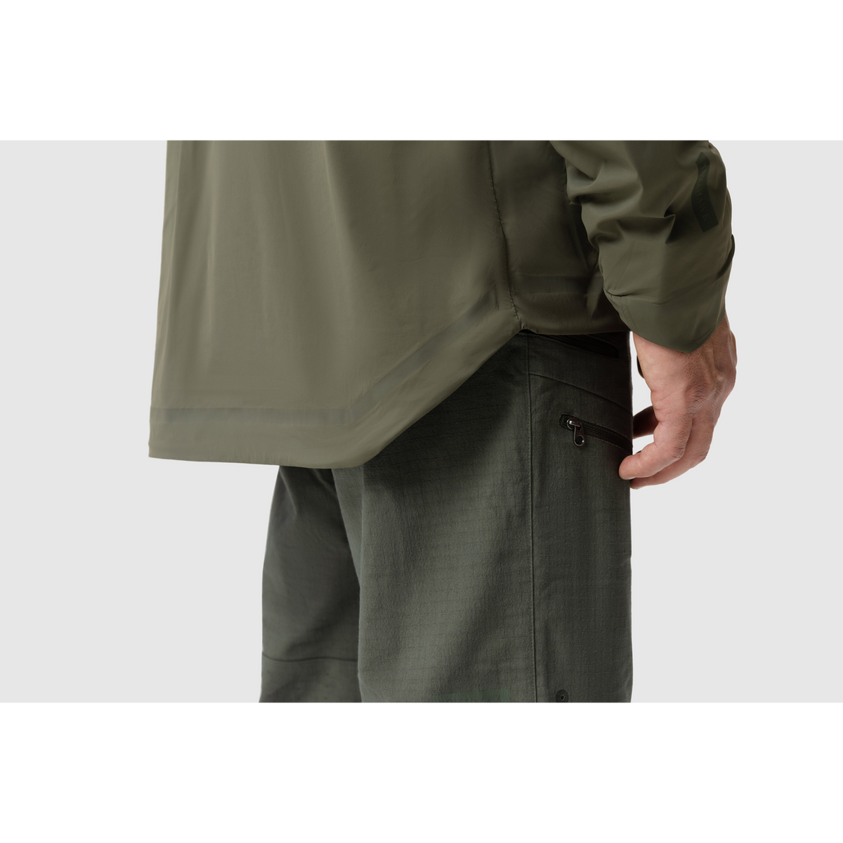 Side close-up photo of the Tomahawk Performance Crosswind Jacket's hem featuring the dropped back seat for coverage and wind protection.